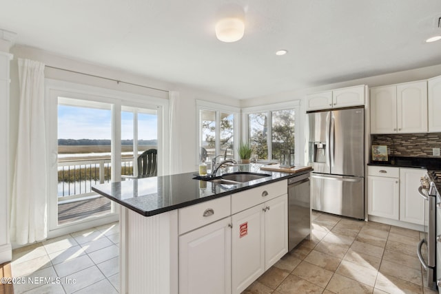 kitchen with white cabinets, a center island with sink, a water view, and stainless steel appliances