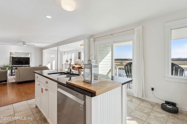 kitchen with white cabinetry, sink, stainless steel dishwasher, a center island with sink, and light tile patterned floors