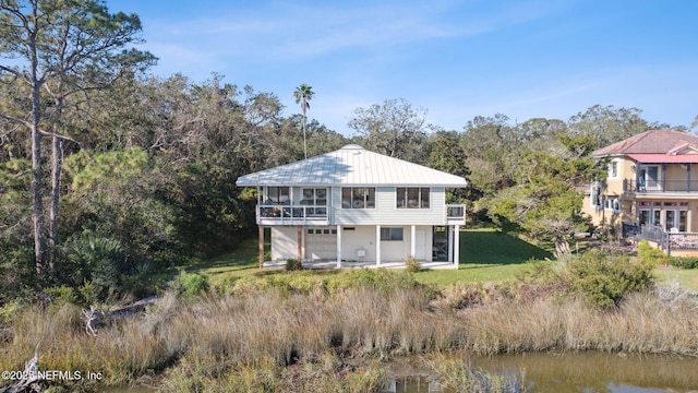 back of house with a lawn, a balcony, and a water view