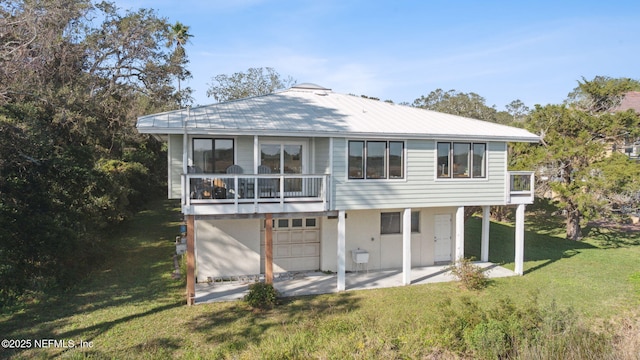 rear view of property with a lawn, a patio area, a garage, and a balcony