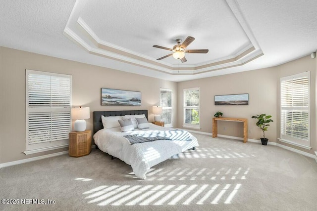 carpeted bedroom featuring ceiling fan, ornamental molding, a textured ceiling, and a tray ceiling