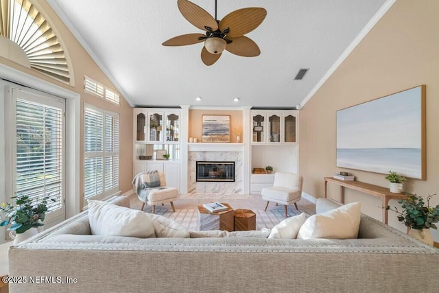 living room with a fireplace, ornamental molding, ceiling fan, and lofted ceiling