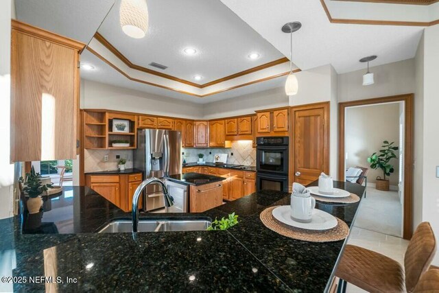 kitchen featuring a tray ceiling, double oven, sink, stainless steel fridge with ice dispenser, and hanging light fixtures