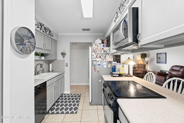 kitchen featuring crown molding, sink, light tile patterned floors, a textured ceiling, and stainless steel appliances