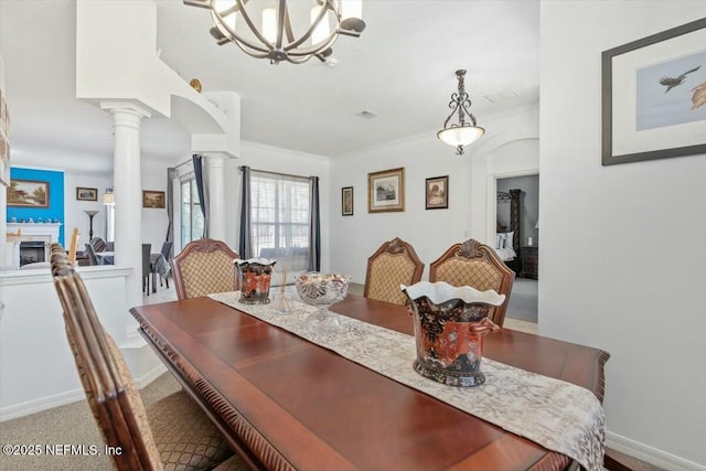 dining space featuring an inviting chandelier, crown molding, and decorative columns