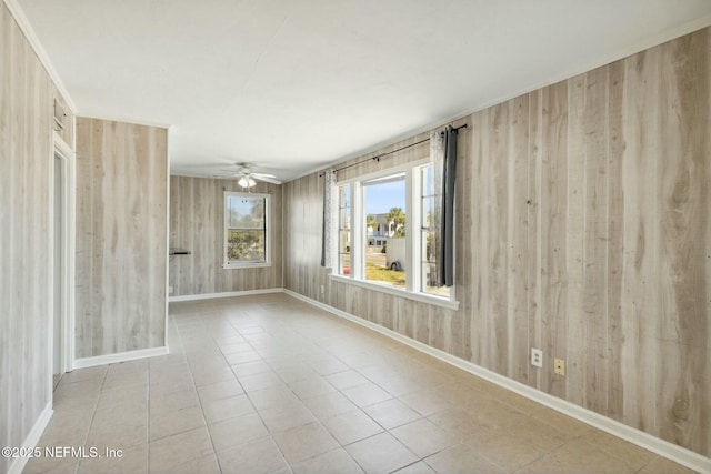 unfurnished room with ceiling fan, light tile patterned floors, and wood walls