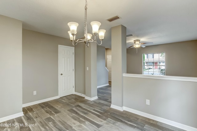 empty room with ceiling fan with notable chandelier and wood-type flooring