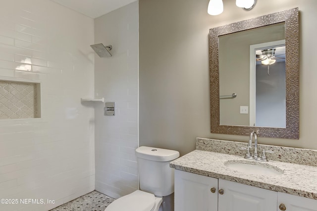 bathroom featuring tiled shower, ceiling fan, vanity, and toilet