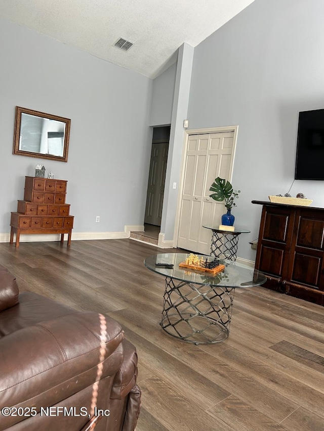 living room with high vaulted ceiling, a textured ceiling, and hardwood / wood-style flooring