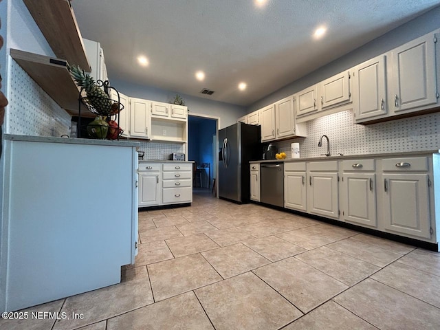 kitchen featuring stainless steel appliances, white cabinetry, tasteful backsplash, and sink