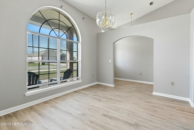 unfurnished dining area with plenty of natural light, light wood-type flooring, lofted ceiling, and an inviting chandelier