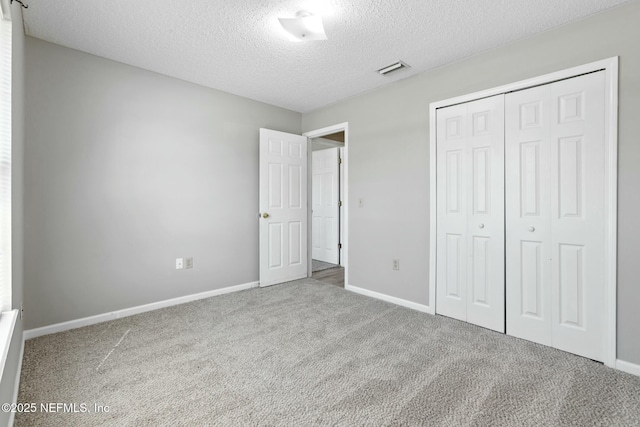 unfurnished bedroom featuring carpet flooring, a textured ceiling, and a closet