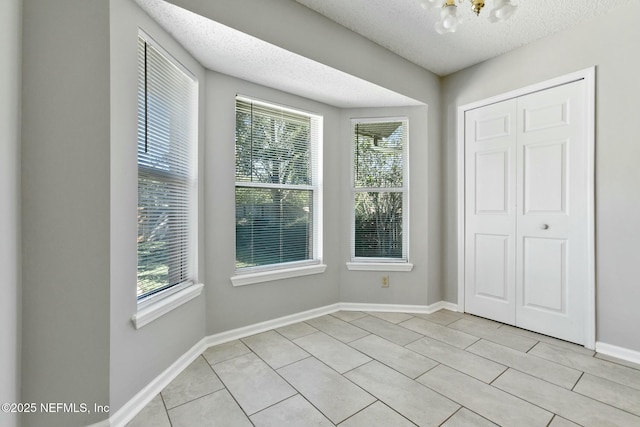 interior space featuring a closet, multiple windows, a textured ceiling, and an inviting chandelier