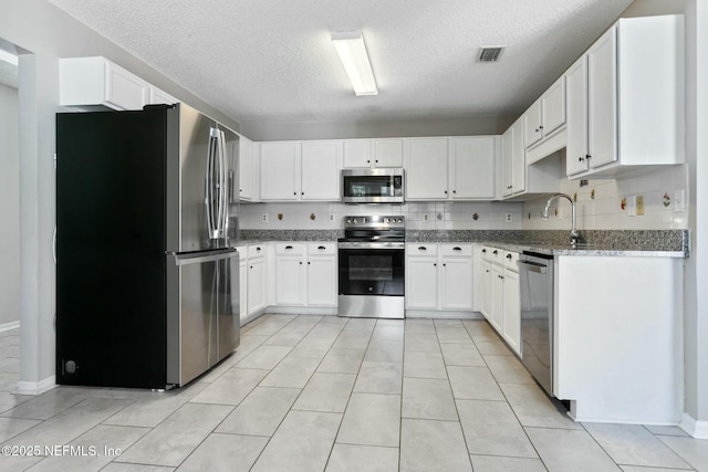 kitchen with backsplash, white cabinetry, light stone counters, and appliances with stainless steel finishes