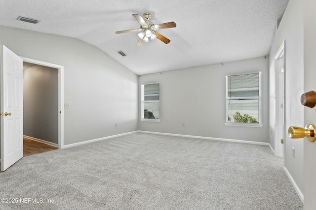 empty room with carpet, plenty of natural light, a textured ceiling, and vaulted ceiling