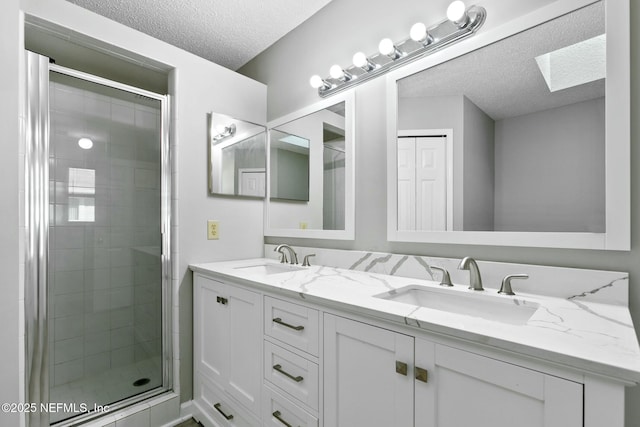 bathroom featuring a skylight, vanity, an enclosed shower, and a textured ceiling