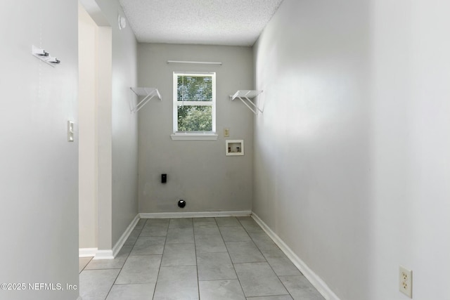 clothes washing area with hookup for a washing machine, a textured ceiling, and light tile patterned floors