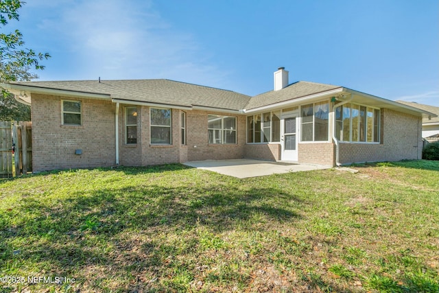 rear view of house with a sunroom, a patio area, and a lawn