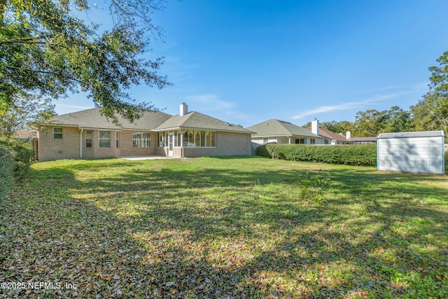 rear view of property featuring a storage unit and a lawn