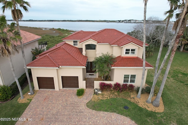 mediterranean / spanish-style house featuring a water view, a garage, and a front lawn