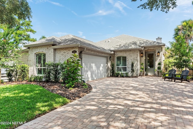 1669 Linkside Ct N, Atlantic Beach, FL 32233 - french country style house featuring an attached garage, brick siding, driveway, a chimney, and a shingled roof