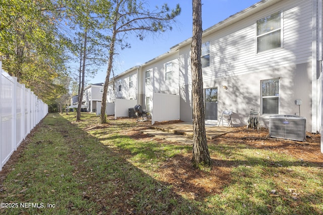 rear view of property featuring central AC unit and a yard