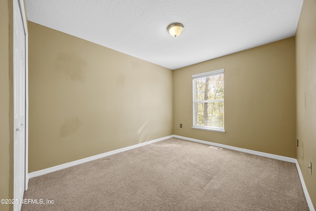 spare room featuring a textured ceiling and carpet flooring