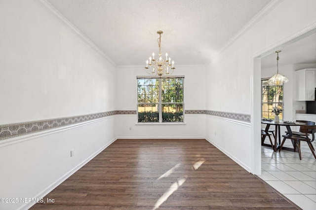 unfurnished dining area with a notable chandelier, dark hardwood / wood-style floors, and ornamental molding