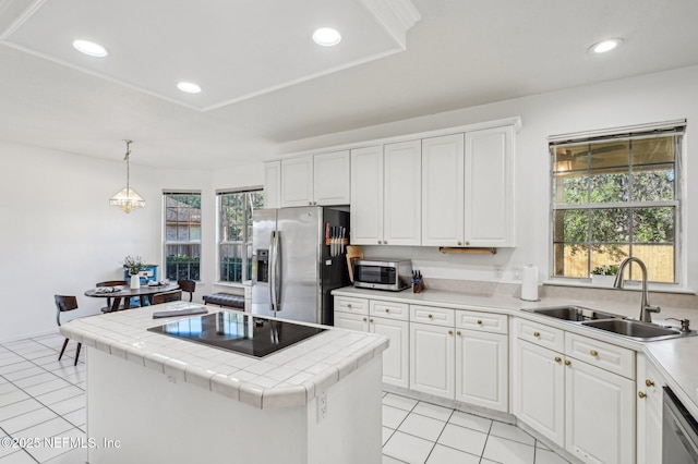 kitchen with tile countertops, white cabinets, sink, hanging light fixtures, and stainless steel appliances