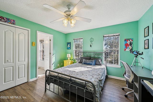 bedroom with ceiling fan, dark hardwood / wood-style floors, a textured ceiling, and a closet