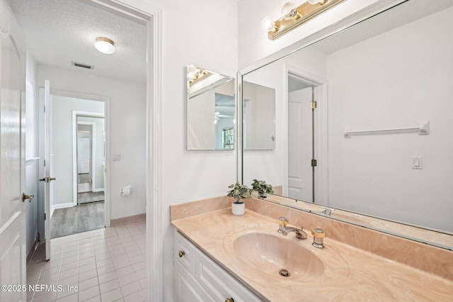 bathroom with tile patterned flooring, vanity, and a textured ceiling