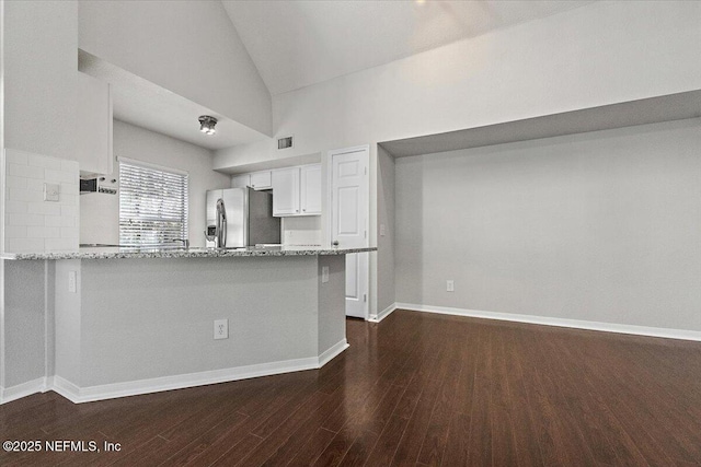 kitchen with kitchen peninsula, white cabinetry, light stone counters, and stainless steel refrigerator with ice dispenser