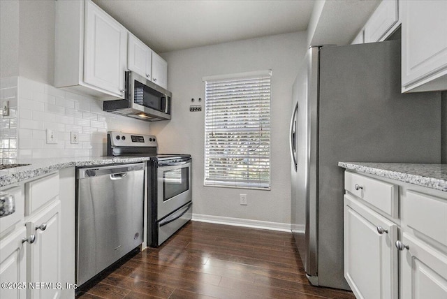 kitchen featuring appliances with stainless steel finishes, backsplash, light stone counters, dark hardwood / wood-style floors, and white cabinetry