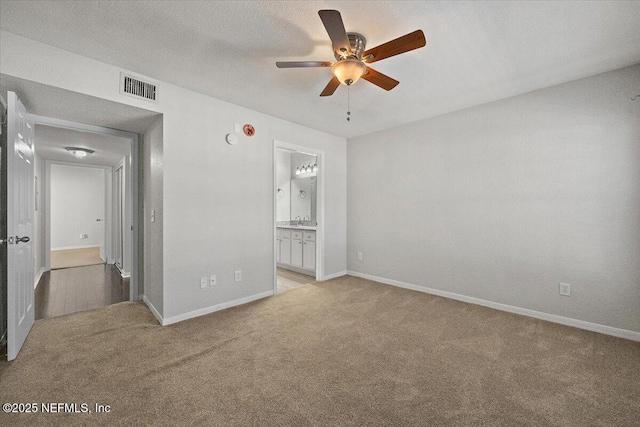 interior space featuring light carpet, ensuite bath, a textured ceiling, ceiling fan, and sink