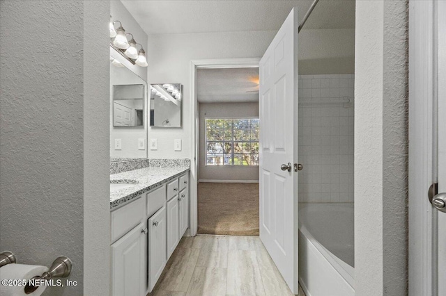 bathroom with hardwood / wood-style floors, vanity, a textured ceiling, and tiled shower / bath combo