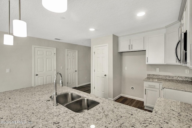 kitchen featuring white cabinets, decorative light fixtures, light stone counters, and sink