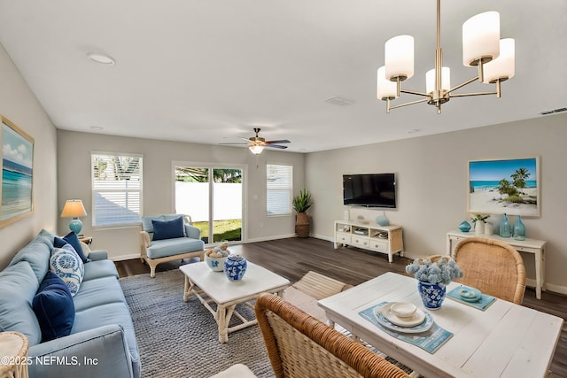 living room featuring ceiling fan with notable chandelier and dark wood-type flooring