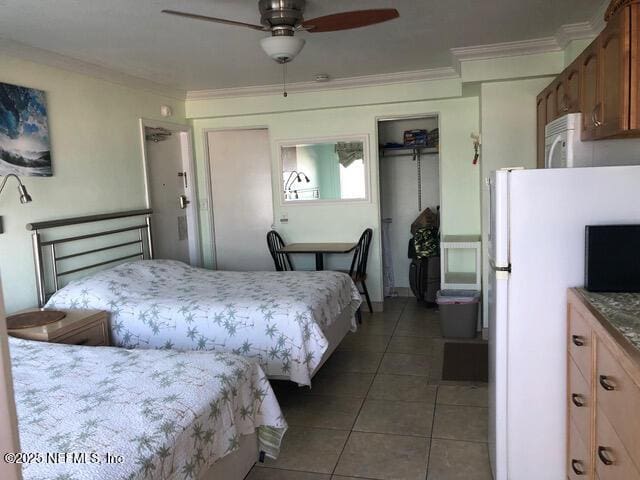 bedroom featuring ceiling fan, crown molding, white refrigerator, tile patterned flooring, and a closet