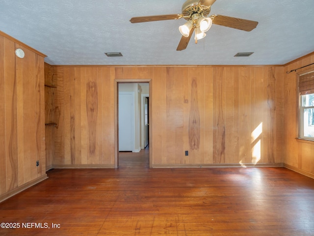 empty room with ceiling fan, dark hardwood / wood-style flooring, and wooden walls