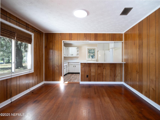 kitchen featuring white cabinetry, dark hardwood / wood-style floors, white refrigerator, kitchen peninsula, and wood walls