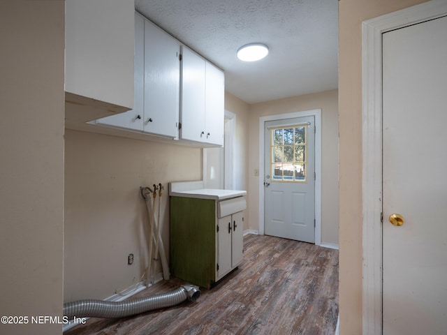 laundry area with cabinets, a textured ceiling, and hardwood / wood-style flooring