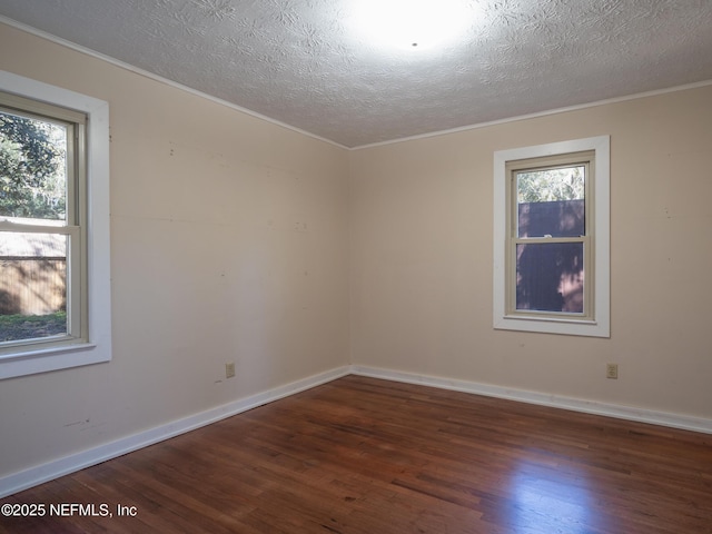 spare room featuring a healthy amount of sunlight, dark hardwood / wood-style flooring, ornamental molding, and a textured ceiling