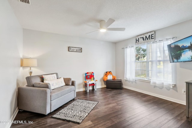 living area with a textured ceiling, ceiling fan, and dark hardwood / wood-style floors