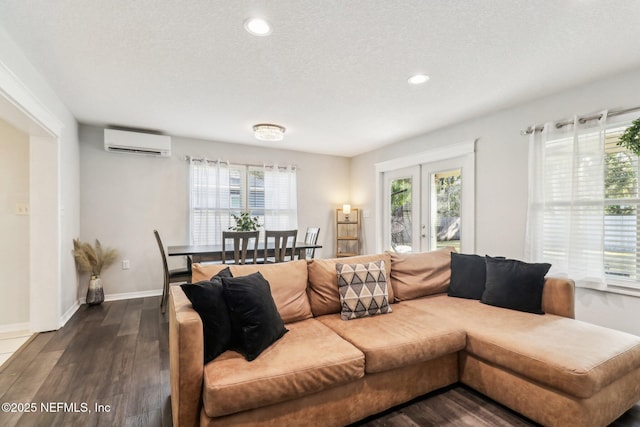 living room with a textured ceiling, a healthy amount of sunlight, dark wood-type flooring, and a wall mounted air conditioner