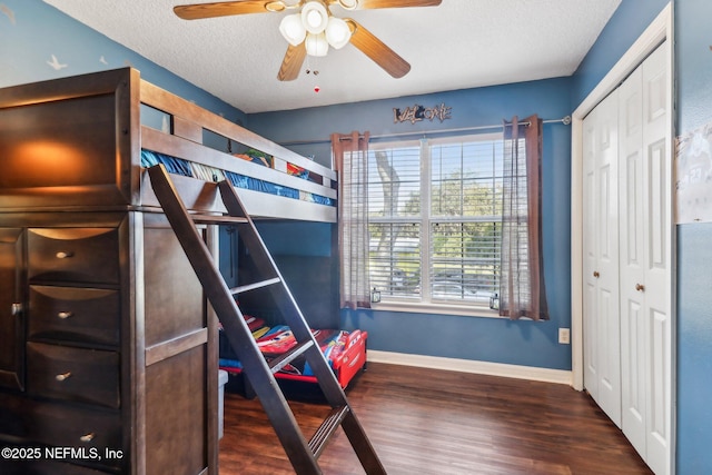 unfurnished bedroom featuring a textured ceiling, ceiling fan, dark wood-type flooring, and a closet