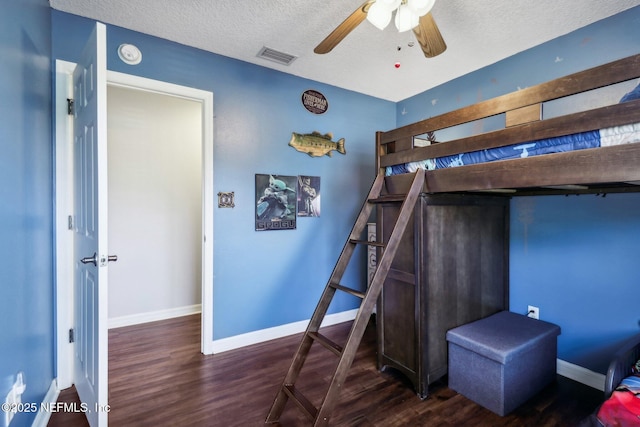 bedroom with a textured ceiling, ceiling fan, and dark wood-type flooring