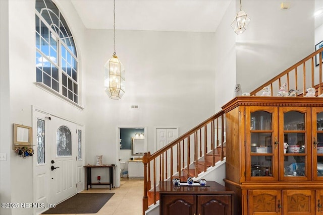 tiled foyer entrance featuring a high ceiling and an inviting chandelier