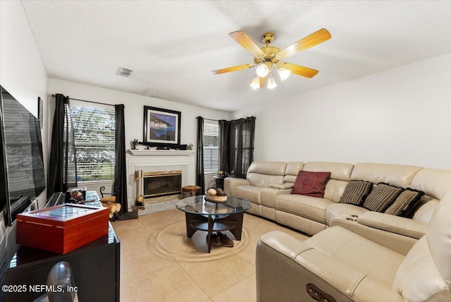 living room featuring ceiling fan, light tile patterned flooring, and a textured ceiling