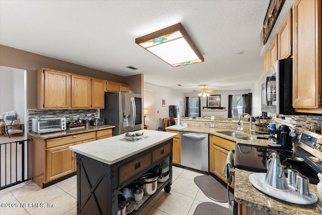 kitchen featuring backsplash, ceiling fan, a center island, and appliances with stainless steel finishes