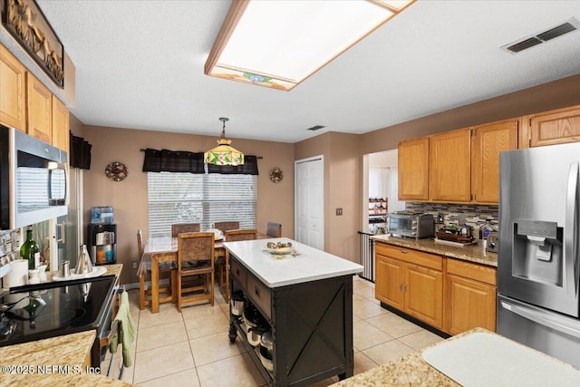 kitchen featuring pendant lighting, light tile patterned flooring, appliances with stainless steel finishes, tasteful backsplash, and a kitchen island